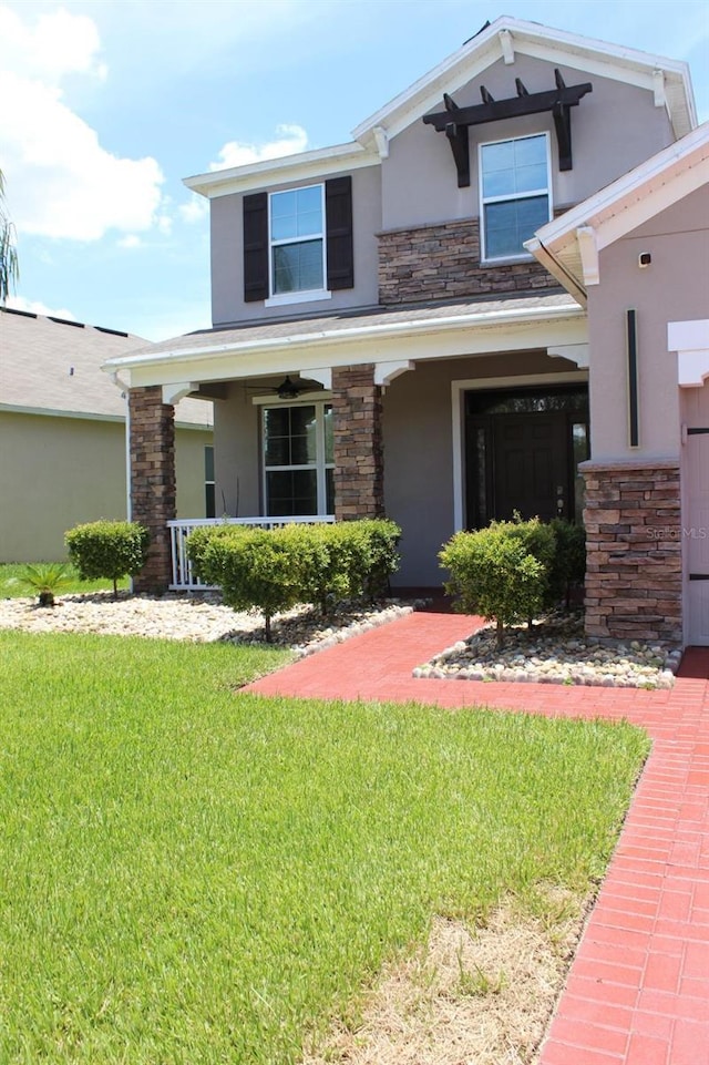 2805 Carter Grove Ln, Kissimmee, FL 34741 - view of front facade featuring stucco siding, stone siding, a porch, and a front yard