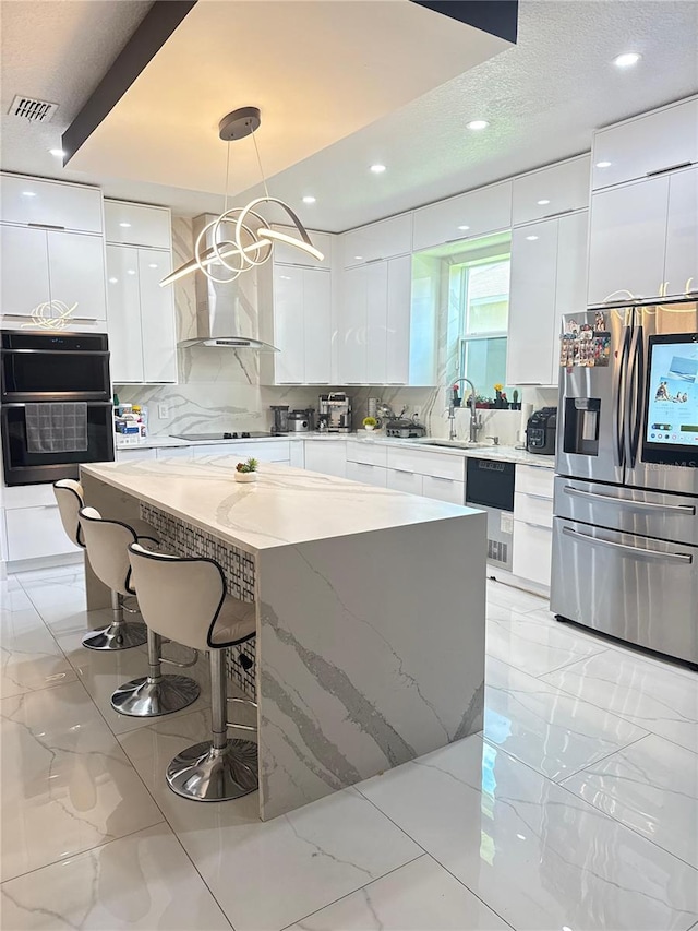 2805 Carter Grove Ln, Kissimmee, FL 34741 - kitchen with black appliances, modern cabinets, wall chimney exhaust hood, white cabinetry, and a kitchen breakfast bar