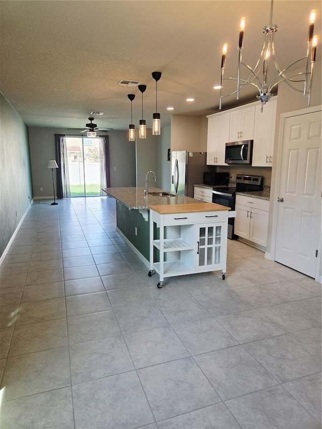 3839 Marbella Way, Davenport, FL 33897 - kitchen with stainless steel appliances, open floor plan, white cabinetry, an island with sink, and a breakfast bar