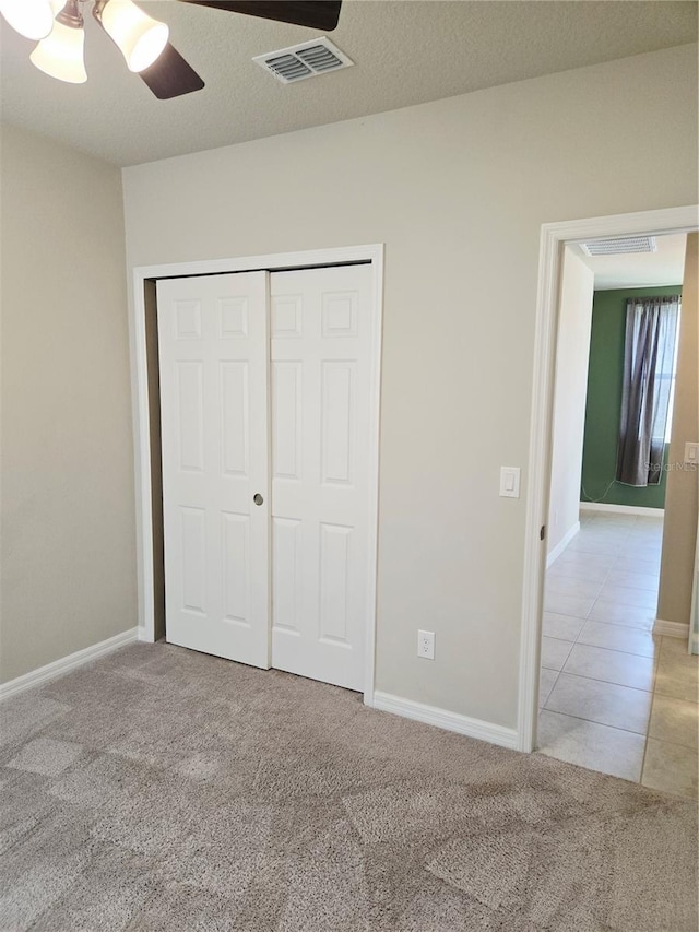 3839 Marbella Way, Davenport, FL 33897 - unfurnished bedroom with carpet flooring, a closet, ceiling fan, and tile patterned floors