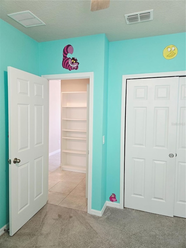 3839 Marbella Way, Davenport, FL 33897 - unfurnished bedroom featuring light carpet, light tile patterned floors, and a closet