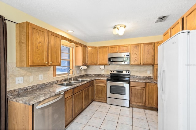 1101 Oregon Ave, Saint Cloud, FL 34769 - kitchen with stainless steel appliances, dark countertops, decorative backsplash, brown cabinetry, and light tile patterned flooring