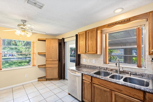 1101 Oregon Ave, Saint Cloud, FL 34769 - kitchen featuring dishwasher, light tile patterned floors, plenty of natural light, brown cabinetry, and a textured ceiling