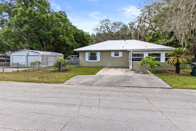 1101 Oregon Ave, Saint Cloud, FL 34769 - view of front facade featuring stucco siding, an outdoor structure, a garage, a metal roof, and view of wooded area