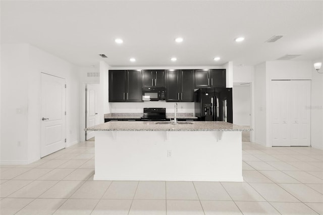 371 Pinecrest Loop, Davenport, FL 33837 - kitchen with black appliances, dark cabinetry, a kitchen island with sink, a breakfast bar, and light tile patterned floors