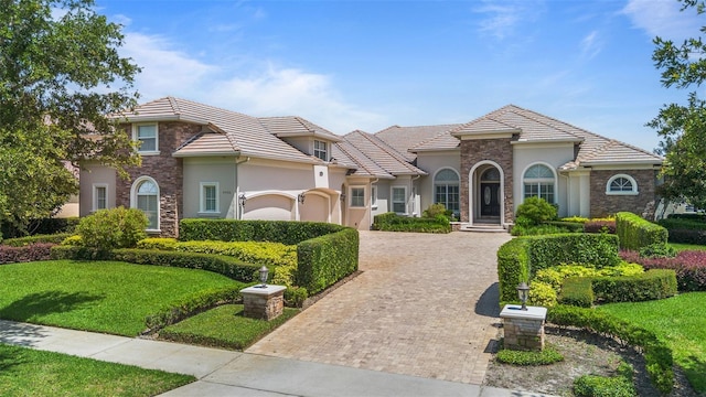 9905 Lanai View Ct, Windermere, FL 34786 - view of front facade featuring stucco siding, decorative driveway, stone siding, a front yard, and a tile roof