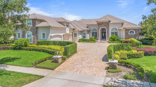 9905 Lanai View Ct, Windermere, FL 34786 - view of front facade with decorative driveway, stucco siding, stone siding, a garage, and a front lawn