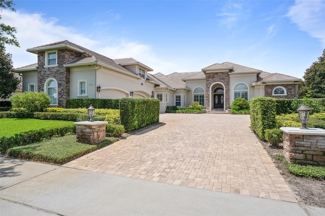 9905 Lanai View Ct, Windermere, FL 34786 - mediterranean / spanish-style house with stucco siding, decorative driveway, an attached garage, and stone siding