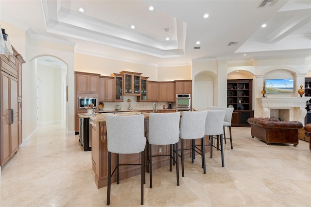 9905 Lanai View Ct, Windermere, FL 34786 - kitchen with appliances with stainless steel finishes, a spacious island, arched walkways, a kitchen breakfast bar, and decorative backsplash