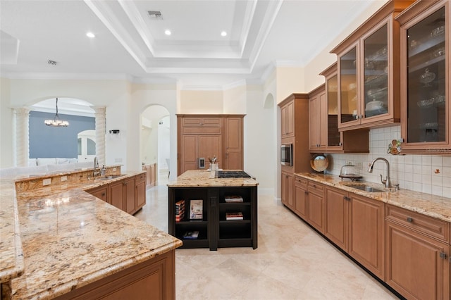 9905 Lanai View Ct, Windermere, FL 34786 - kitchen featuring arched walkways, ornate columns, brown cabinetry, light stone countertops, and crown molding