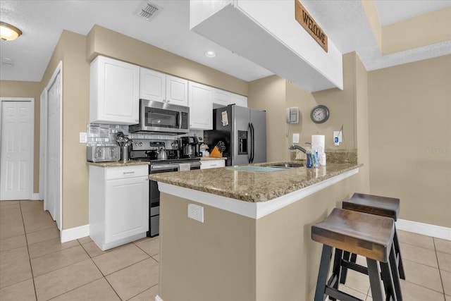 2737 N Poinciana Blvd Unit 92, Kissimmee, FL 34746 - kitchen featuring stainless steel appliances, light tile patterned floors, a breakfast bar, a peninsula, and white cabinetry