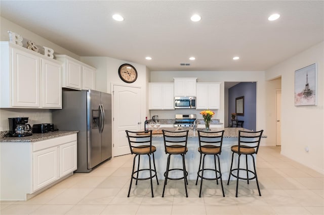 5231 Wildwood Way, Davenport, FL 33837 - kitchen featuring appliances with stainless steel finishes, white cabinetry, a breakfast bar, recessed lighting, and a kitchen island with sink