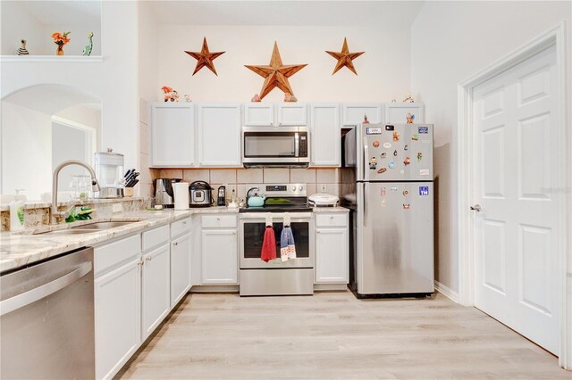 1014 Prey Ct, Kissimmee, FL 34746 - kitchen with stainless steel appliances, tasteful backsplash, white cabinetry, light wood finished floors, and light stone counters