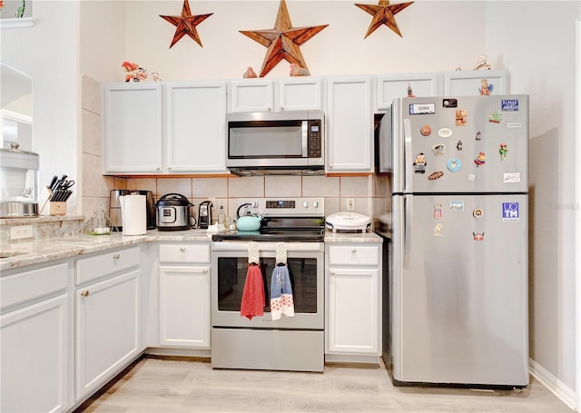 1014 Prey Ct, Kissimmee, FL 34746 - kitchen featuring appliances with stainless steel finishes, backsplash, light wood-style flooring, and white cabinetry