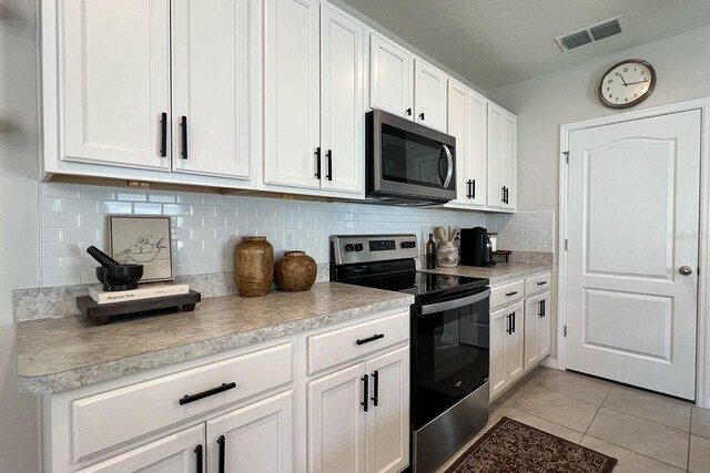 2727 Harmonia Hammock Rd, Harmony, FL 34773 - kitchen featuring stainless steel appliances, white cabinets, light tile patterned flooring, light countertops, and backsplash