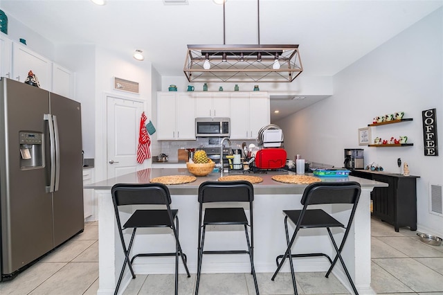 1959 Cricket Cradle Dr, Kissimmee, FL 34746 - kitchen featuring appliances with stainless steel finishes, white cabinetry, a kitchen bar, decorative backsplash, and recessed lighting