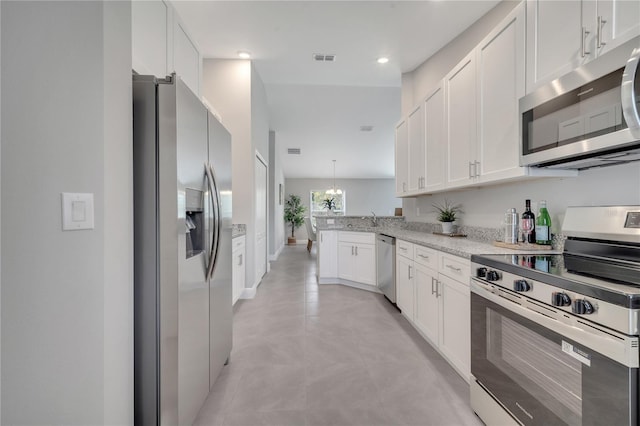 33 Peterlee Ct, Kissimmee, FL 34758 - kitchen with appliances with stainless steel finishes, a peninsula, white cabinets, light stone counters, and recessed lighting