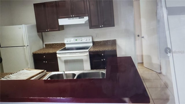 2002 Cascades Blvd Unit 108, Kissimmee, FL 34741 - kitchen with white appliances, under cabinet range hood, dark countertops, and light tile patterned floors