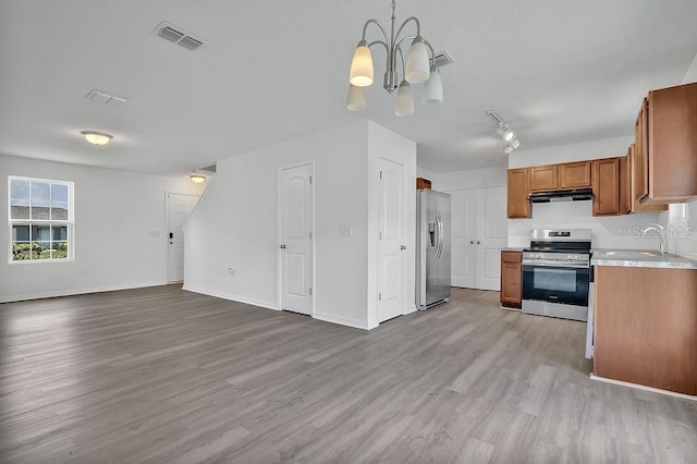 303 Anchovie Ct, Poinciana, FL 34759 - kitchen featuring stainless steel appliances, brown cabinets, a chandelier, and light wood-style floors
