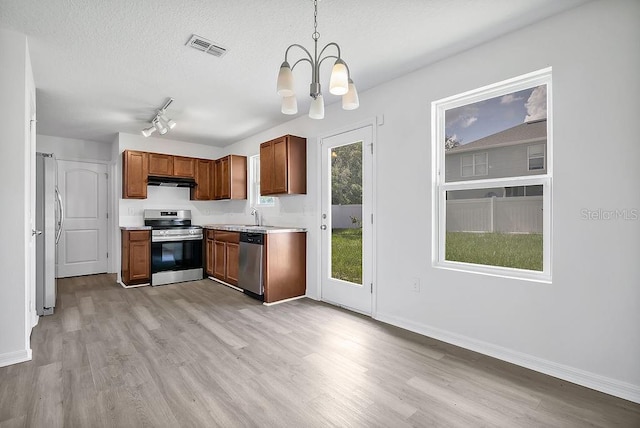 303 Anchovie Ct, Poinciana, FL 34759 - kitchen featuring stainless steel appliances, a chandelier, light wood-style flooring, light countertops, and a textured ceiling