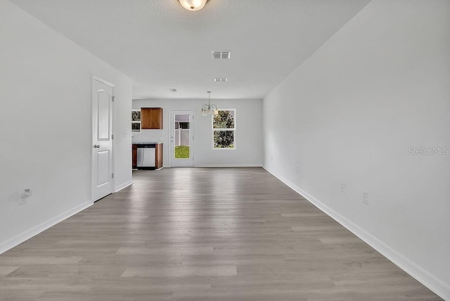 303 Anchovie Ct, Poinciana, FL 34759 - unfurnished living room featuring wood finished floors and a chandelier
