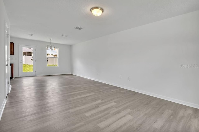 303 Anchovie Ct, Poinciana, FL 34759 - unfurnished room featuring wood finished floors and a chandelier