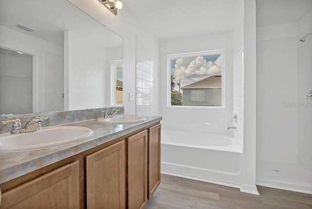 303 Anchovie Ct, Poinciana, FL 34759 - full bathroom featuring wood finished floors, a bath, double vanity, and a shower