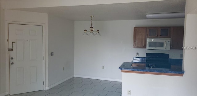 5287 Images Cir Unit 307, Kissimmee, FL 34746 - kitchen featuring white microwave, tile patterned floors, electric range oven, a chandelier, and dark countertops