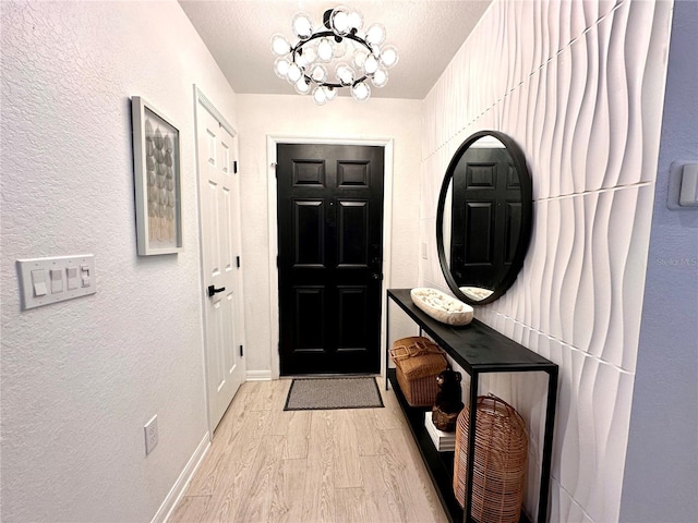 144 Foxtail Loop, Davenport, FL 33837 - doorway featuring light wood finished floors, a textured wall, a chandelier, and a textured ceiling