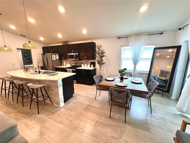 144 Foxtail Loop, Davenport, FL 33837 - kitchen featuring stainless steel appliances, light wood-type flooring, an island with sink, a kitchen bar, and light countertops