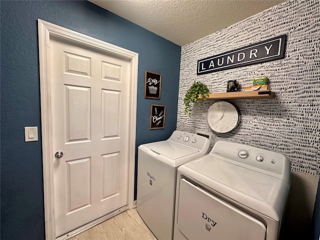 144 Foxtail Loop, Davenport, FL 33837 - washroom with washing machine and clothes dryer, light wood-style floors, a textured ceiling, and an accent wall