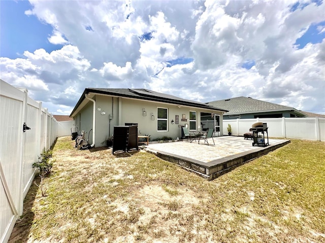 144 Foxtail Loop, Davenport, FL 33837 - rear view of house with solar panels, a fenced backyard, a patio, and stucco siding
