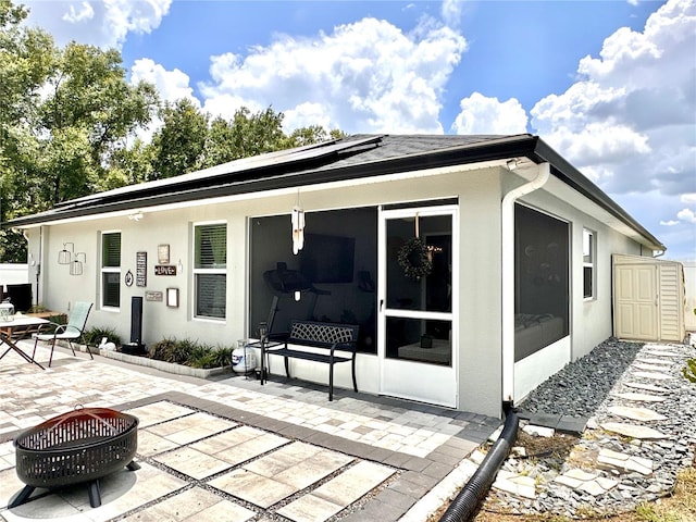144 Foxtail Loop, Davenport, FL 33837 - rear view of property with a patio, solar panels, a fire pit, and stucco siding