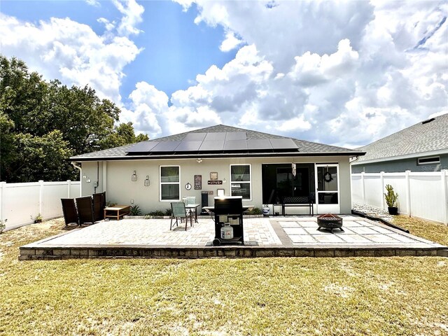 144 Foxtail Loop, Davenport, FL 33837 - rear view of property with an outdoor fire pit, roof mounted solar panels, a patio, and a fenced backyard