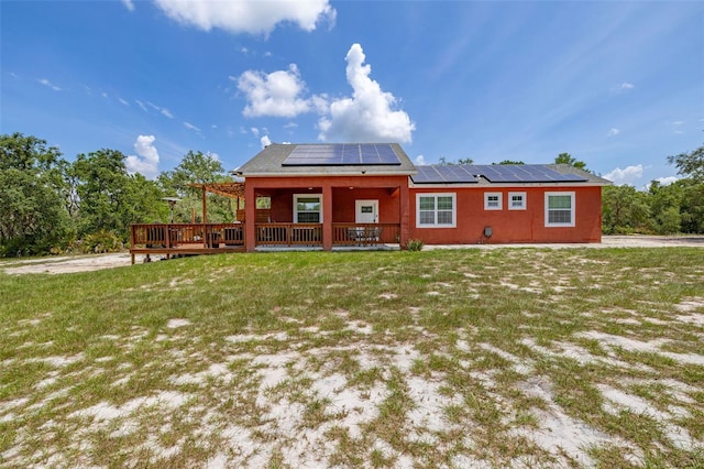 2576 R E Byrd Rd, Frostproof, FL 33843 - rear view of house with roof mounted solar panels, a lawn, and a deck