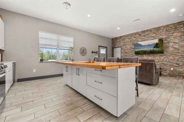2576 R E Byrd Rd, Frostproof, FL 33843 - kitchen featuring butcher block counters, white cabinetry, light wood-style floors, a kitchen breakfast bar, and a kitchen island