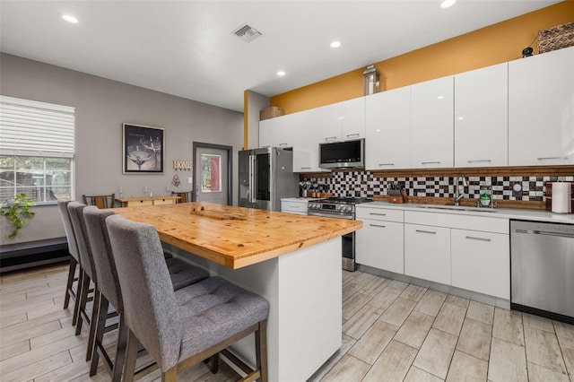 2576 R E Byrd Rd, Frostproof, FL 33843 - kitchen with appliances with stainless steel finishes, a center island, backsplash, a kitchen bar, and recessed lighting