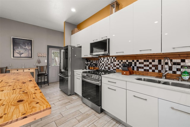 2576 R E Byrd Rd, Frostproof, FL 33843 - kitchen featuring appliances with stainless steel finishes, tasteful backsplash, white cabinetry, light wood-type flooring, and modern cabinets