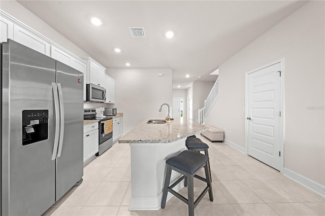 7413 Bent Tree Loop, Saint Cloud, FL 34771 - kitchen featuring stainless steel appliances, white cabinetry, a breakfast bar area, a kitchen island with sink, and light tile patterned floors