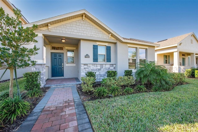 11051 Bostwick Aly, Winter Garden, FL 34787 - view of front facade with stucco siding, stone siding, a front lawn, and a porch