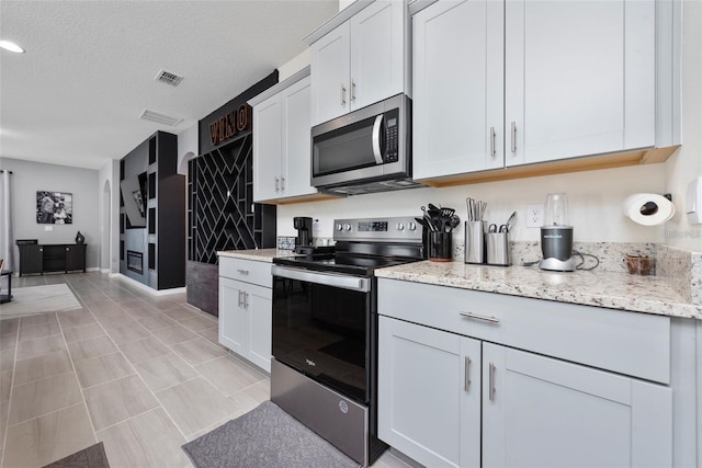 11051 Bostwick Aly, Winter Garden, FL 34787 - kitchen with appliances with stainless steel finishes, white cabinetry, light stone counters, and a textured ceiling