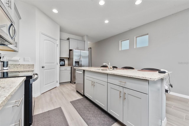 11051 Bostwick Aly, Winter Garden, FL 34787 - kitchen featuring appliances with stainless steel finishes, recessed lighting, an island with sink, gray cabinets, and light stone counters