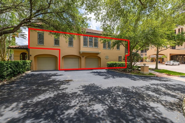 502 Mirasol Cir Unit 103, Kissimmee, FL 34747 - view of front of home featuring a garage, a tiled roof, stucco siding, and driveway