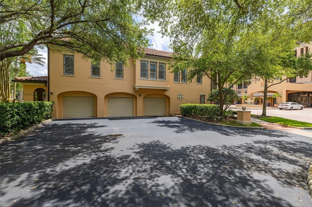 502 Mirasol Cir Unit 103, Kissimmee, FL 34747 - view of front facade with a tile roof, driveway, an attached garage, and stucco siding
