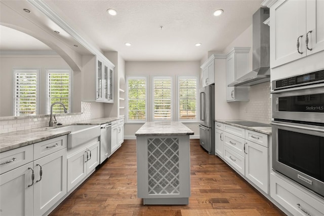 502 Mirasol Cir Unit 103, Kissimmee, FL 34747 - kitchen featuring appliances with stainless steel finishes, wall chimney range hood, white cabinets, a kitchen island, and recessed lighting