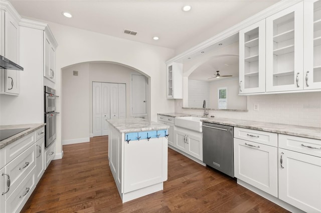 502 Mirasol Cir Unit 103, Kissimmee, FL 34747 - kitchen featuring appliances with stainless steel finishes, arched walkways, white cabinetry, a kitchen island, and recessed lighting