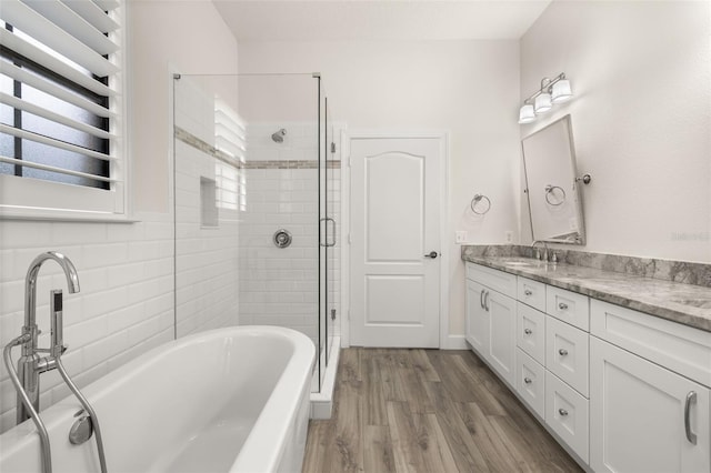 502 Mirasol Cir Unit 103, Kissimmee, FL 34747 - full bath featuring a freestanding tub, double vanity, a stall shower, and wood finished floors