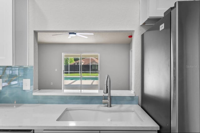 6528 Shepherd Oaks Pass, Lakeland, FL 33811 - kitchen with freestanding refrigerator, white cabinetry, a ceiling fan, and tasteful backsplash