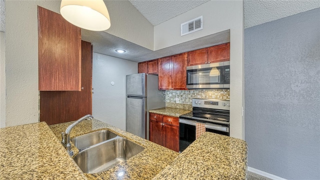 5112 Conroy Rd Unit 24, Orlando, FL 32811 - kitchen featuring appliances with stainless steel finishes, decorative backsplash, a textured ceiling, a textured wall, and light stone counters