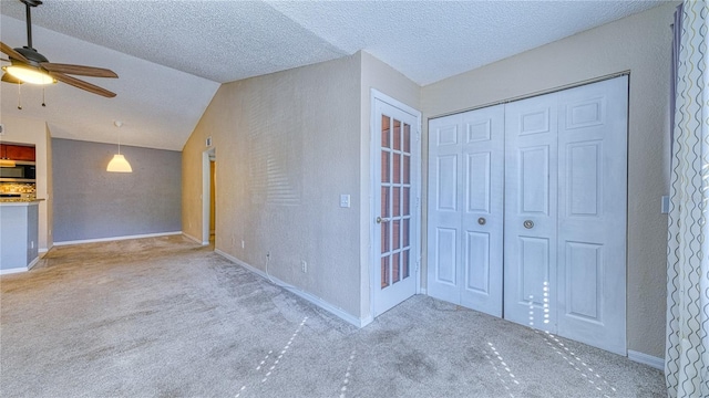 5112 Conroy Rd Unit 24, Orlando, FL 32811 - unfurnished living room featuring carpet floors, a ceiling fan, vaulted ceiling, a textured wall, and a textured ceiling